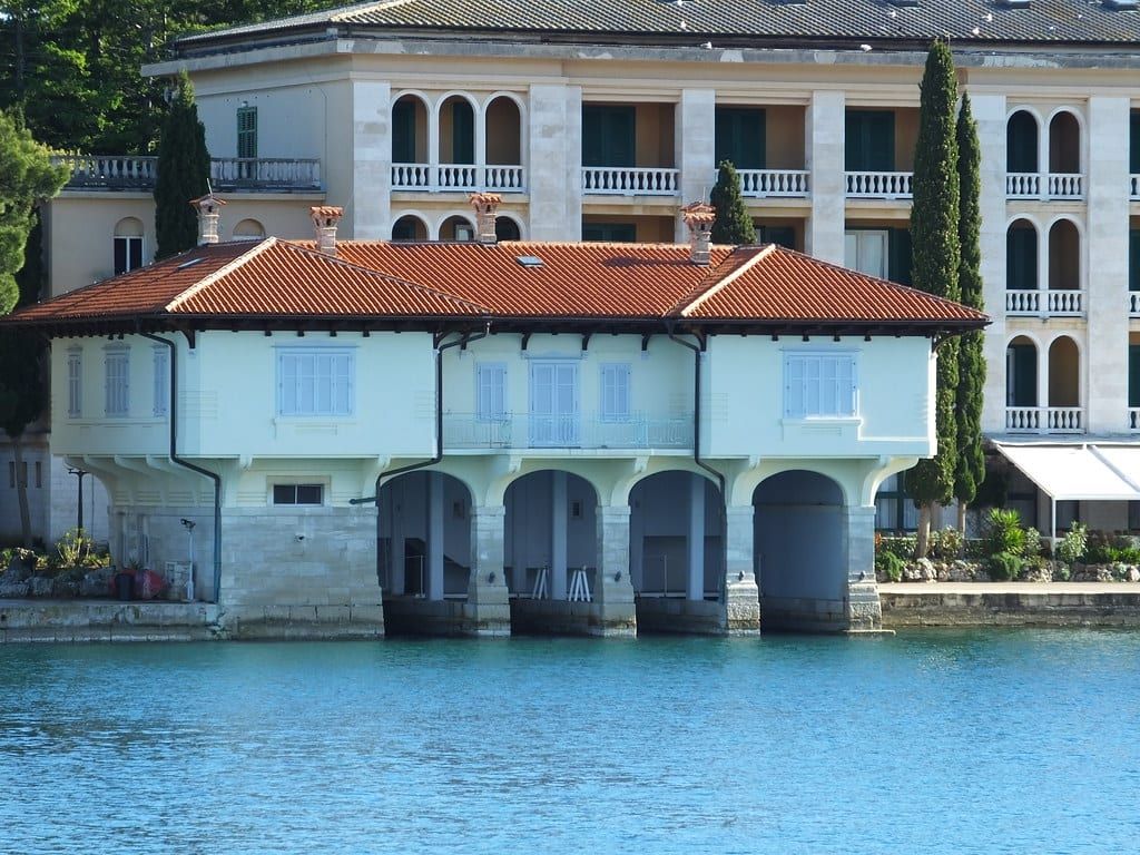 Das historische Bootshaus steht direkt über klarem Küstenwasser im Nationalpark Brijuni.